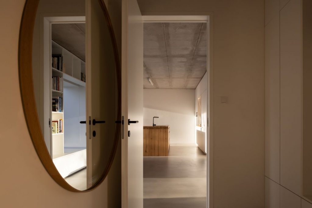 Vstup do spoločenskej miestnosti cez dvere, pri ktorých je veľké okrúhle zrkadlo.