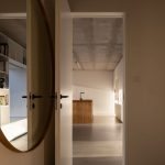Vstup do spoločenskej miestnosti cez dvere, pri ktorých je veľké okrúhle zrkadlo.