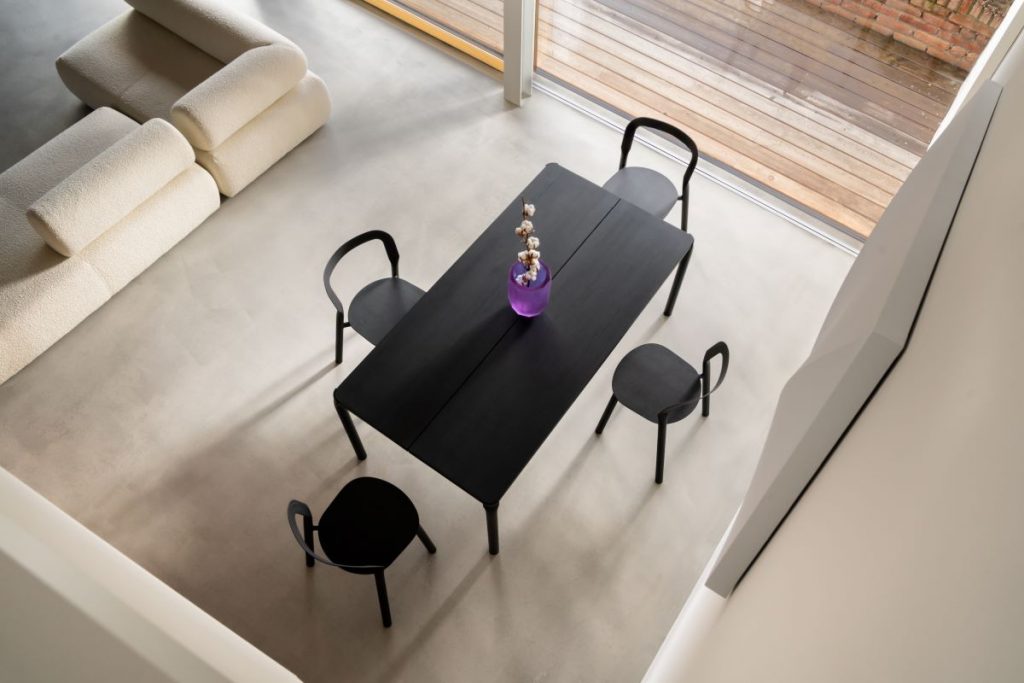 Pohľad zhora na čierny odbĺžnikový jedálenský stôl so štyrmi stoličkami v spoločenskej časti domu.