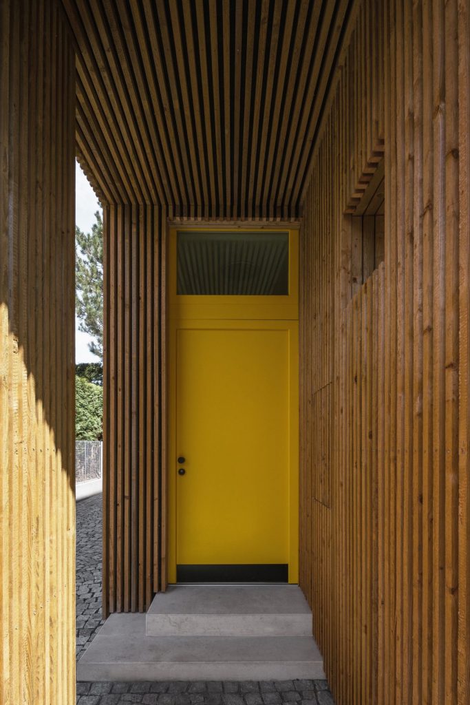 Vstup do domu s dvoma štítmi so žltými dverami.