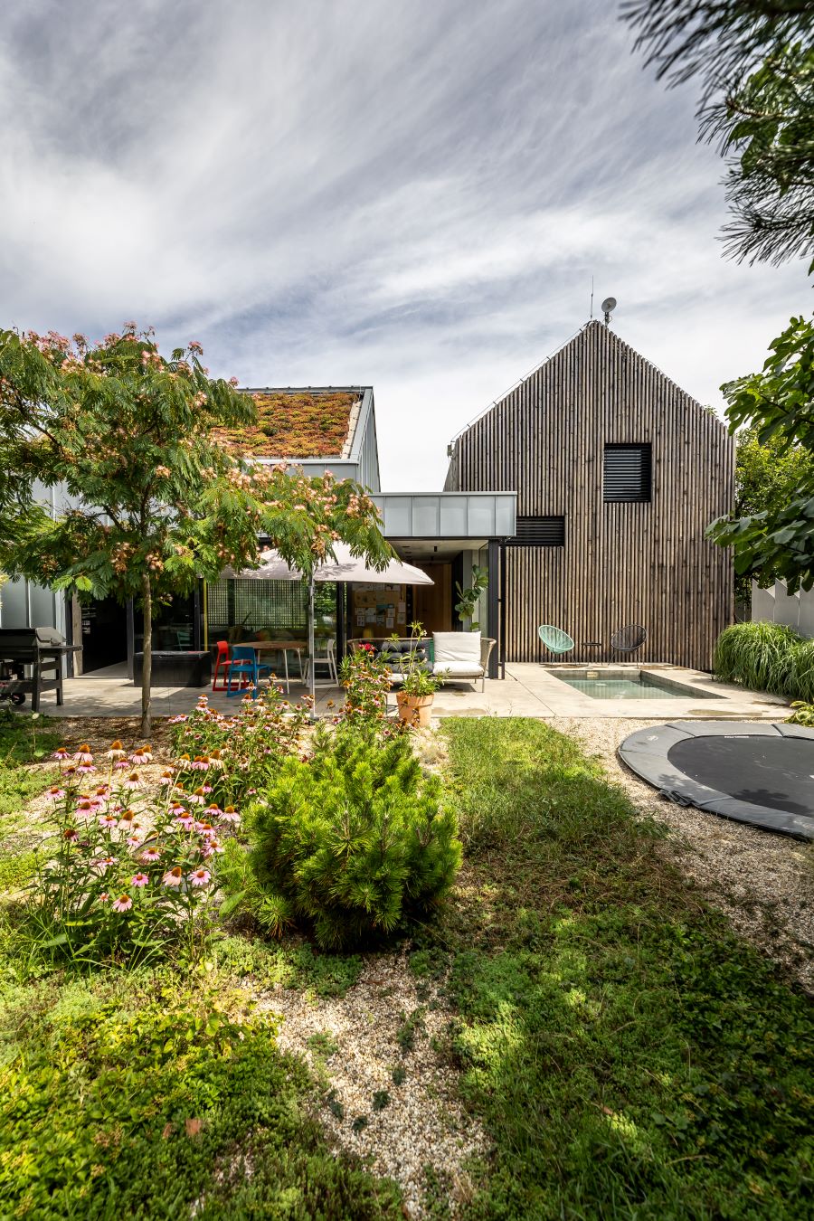 Exteriér domu so záhradou, bazénom a betónovou krytou terasou so záhradným nábytkom.