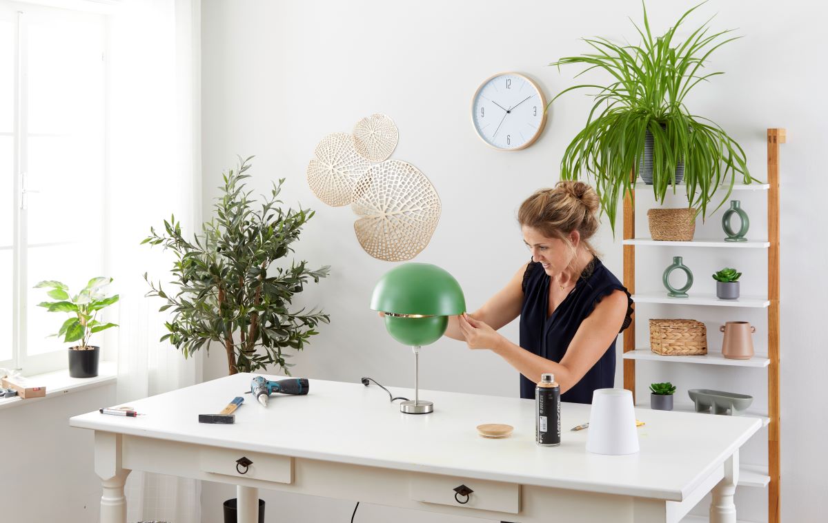 Žena pri pracovnom stole kladie väčšiu misku na menšiu a vytvára tak lampu-