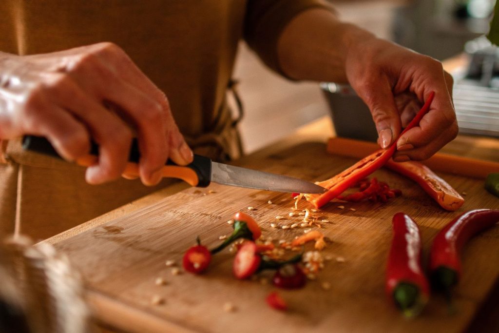 Muž odstraňuje okrajovacím nožom kôstky z jadierka papriky.