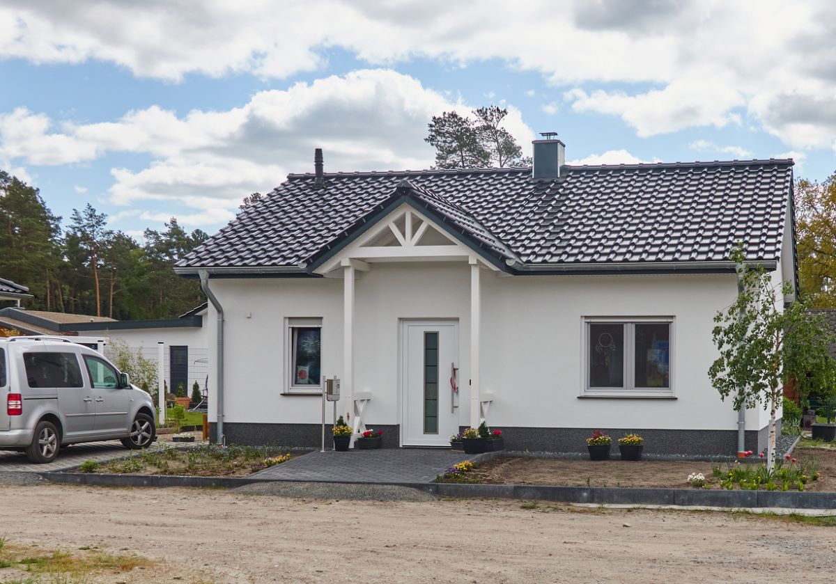 Bungalov v Nemecku s bielou fasádou a tmavou strechou.