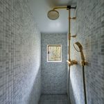 Sprchovací kút s modrosivou mozaikou a malým okienkom.