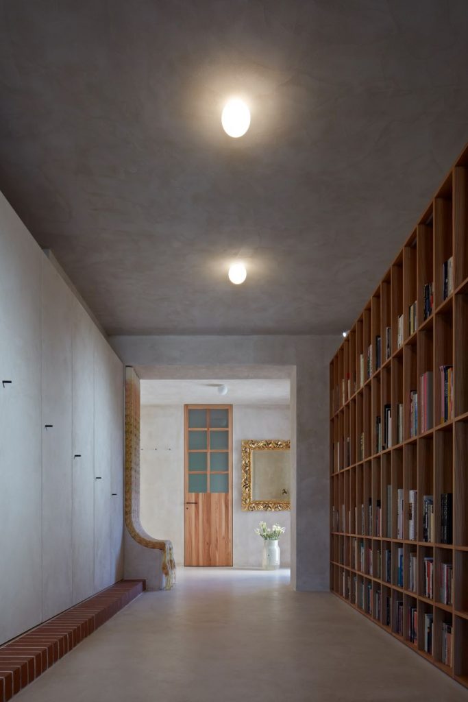 Chodba pri vchode do bytu lemovaná z jednej strany úložným skriňovým priestorom a z druhej rozsiahlou knižnicou.