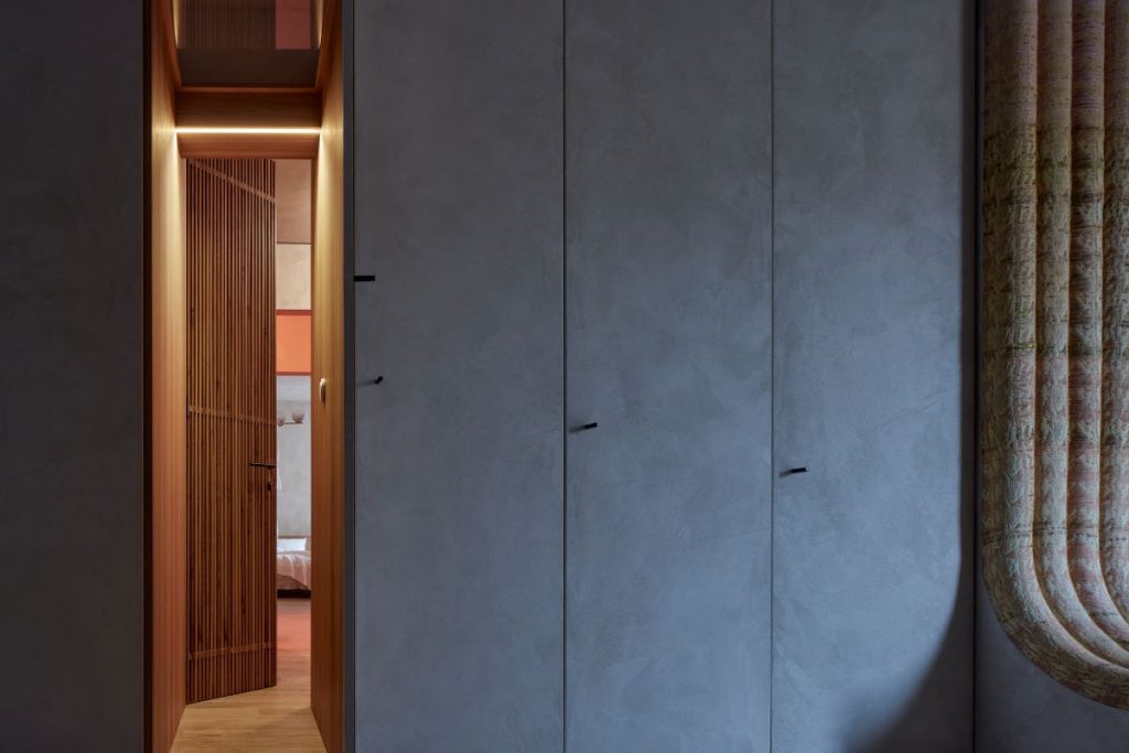 Skriňový úložný priestor na chodbe v minimalistickom dizajne s jednými otvorenými dverami, odhaľujúcimi tajný priechod do spálne.