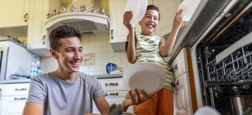 Mladý muž a chlapec vyberajú riady z umývačky riadu.