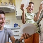 Mladý muž a chlapec vyberajú riady z umývačky riadu.