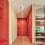 Chodba s drevenými parketami a červenými stenami s dverami v rovnakej farbe.