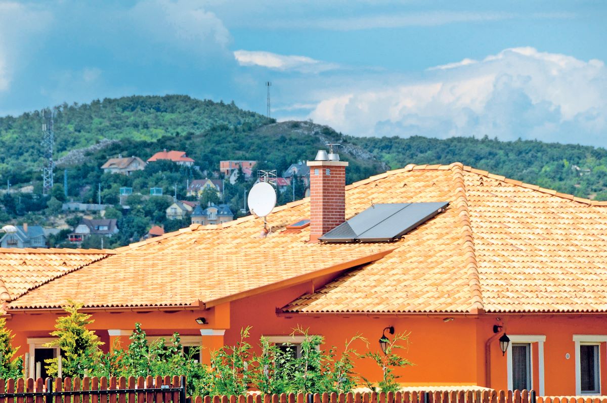 Pohľad na strechu rodinného domu s komínom a fotovoltickým panelom.