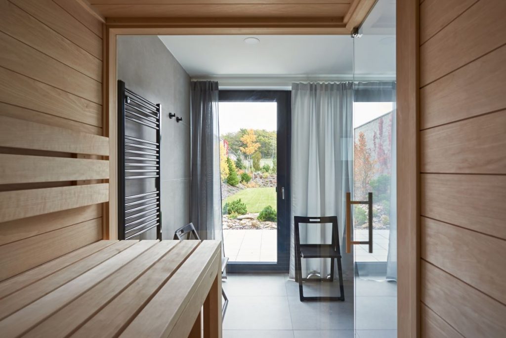 Pohľad zo sauny cez presklené dvere smerom von na dvor.