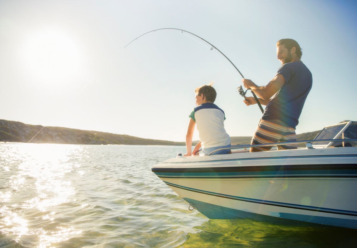 Muž a chlapec na člne spolu lovia ryby.