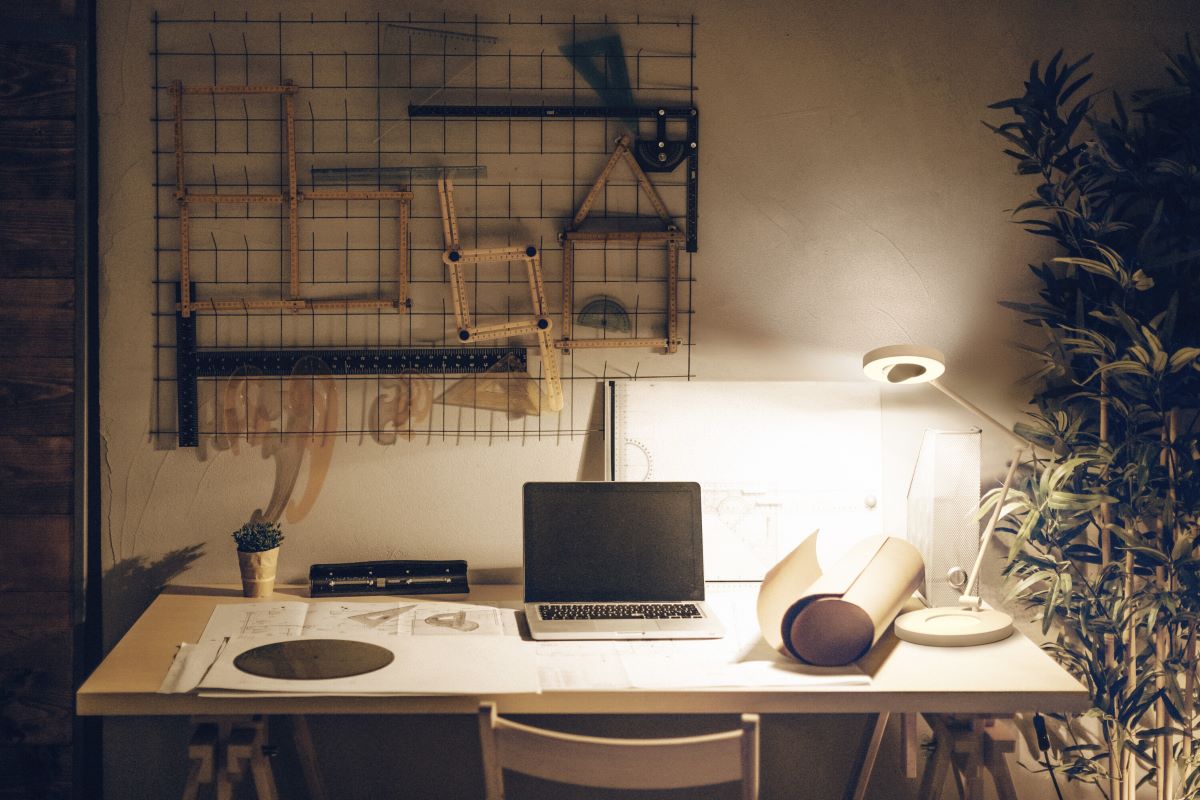 Pracovný stôl s notebookom, osvetlený stolnou lampou.