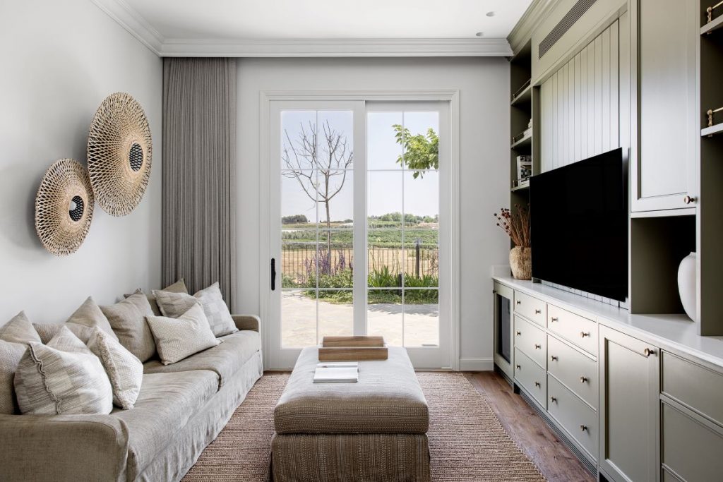Pohľad do obývacej časti domu so sedačkou, televízorom a francúzskym oknom.
