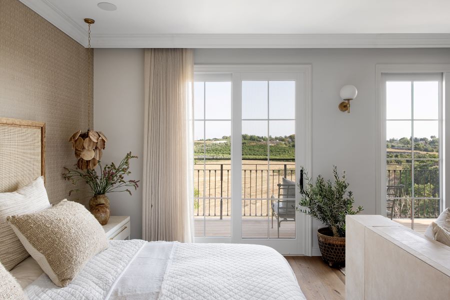 Pohľad v spálni na francúzske okná s výhľadom na prírodu.