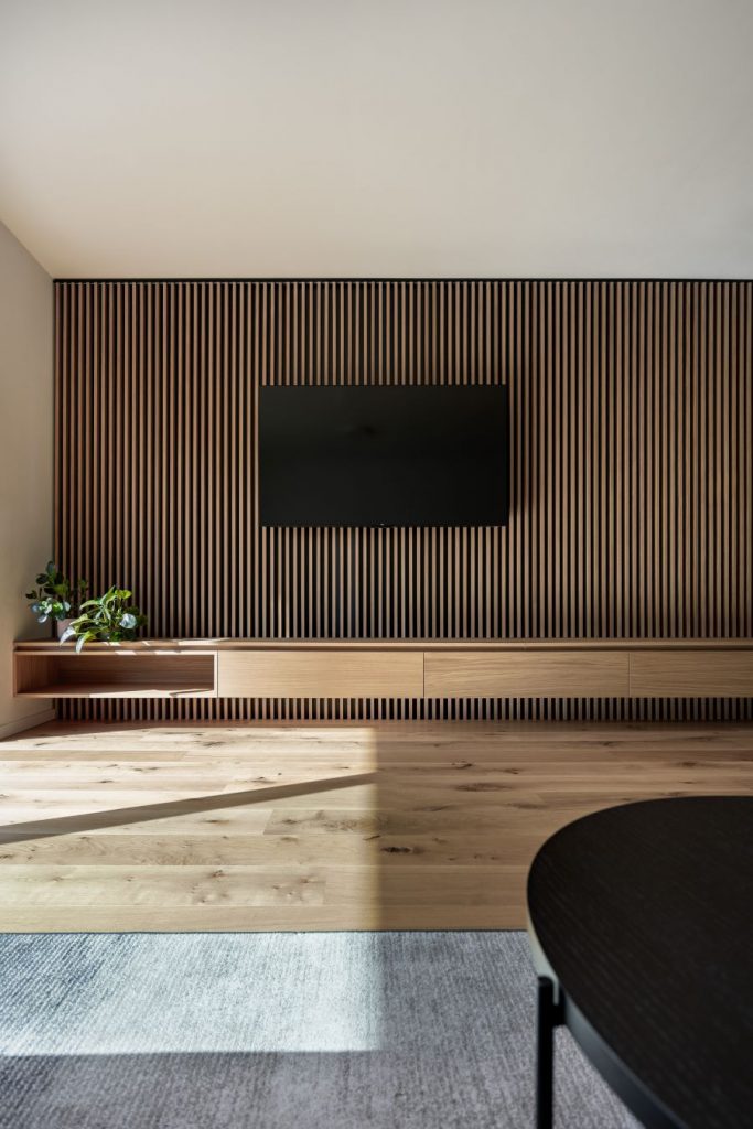 Pohľad na lamelami obloženú stenu v obývačke s televízorom.