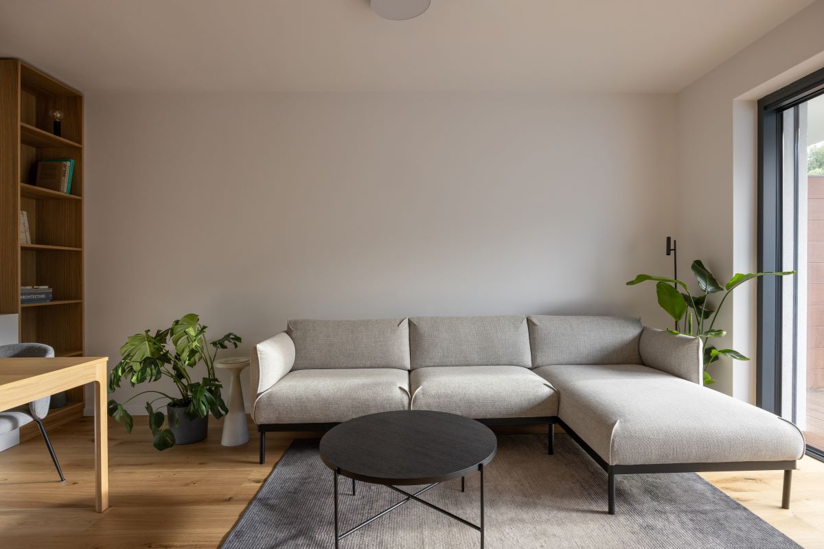 Časť obývačky so sivou sedačkou a okrúhlym konferenčným stolíkom.