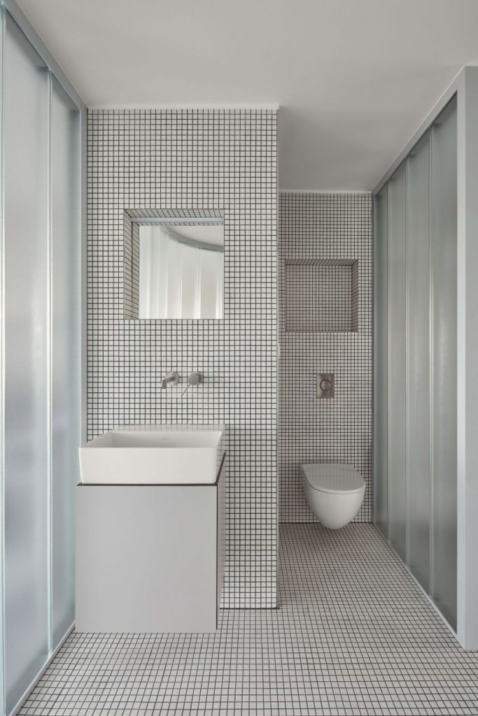 Kúpeľňa s toaletou, umývadlom a mozaikovým obkladom.