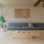 Pohľad do minimalisticky zariadenej obývačky so širokou sedačkou.