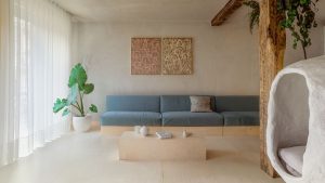 Pohľad do minimalisticky zariadenej obývačky so širokou sedačkou.