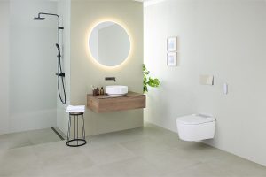 Časť kúpeľne s umývadlom na skrinke, toaletou a okrúhlym podsvieteným zrkadlom.