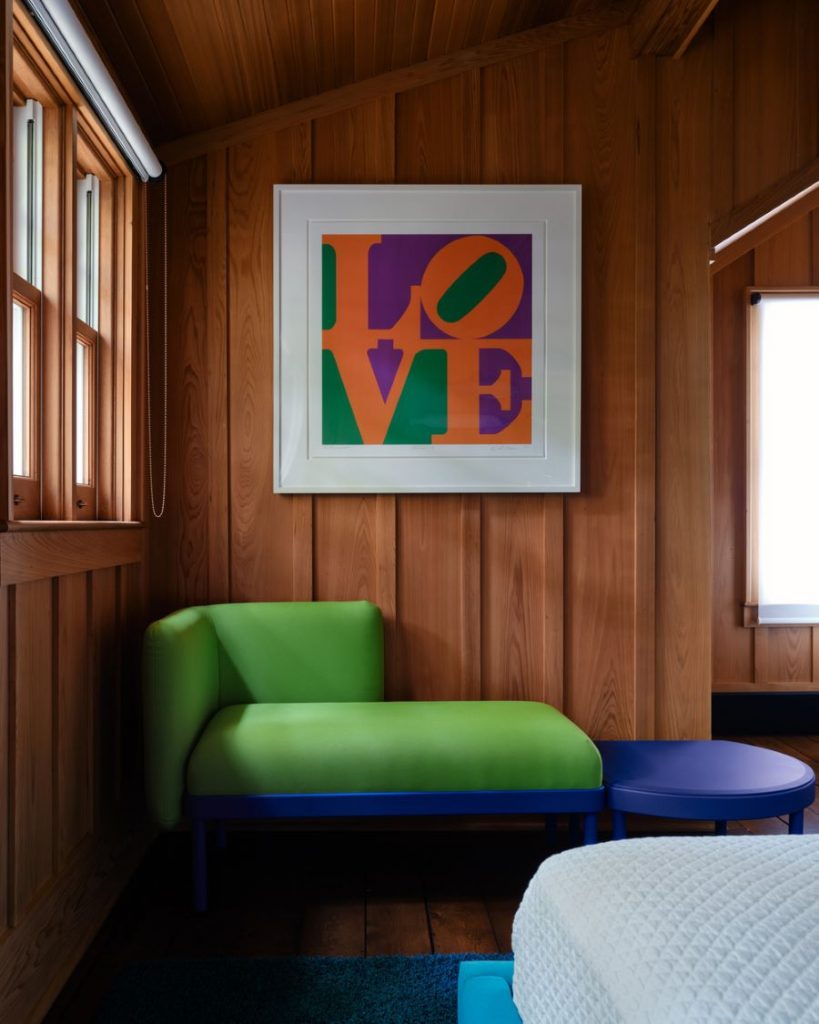 Zelená rohová lavica s modrou konštrukciou pod pop artovým obrazom.