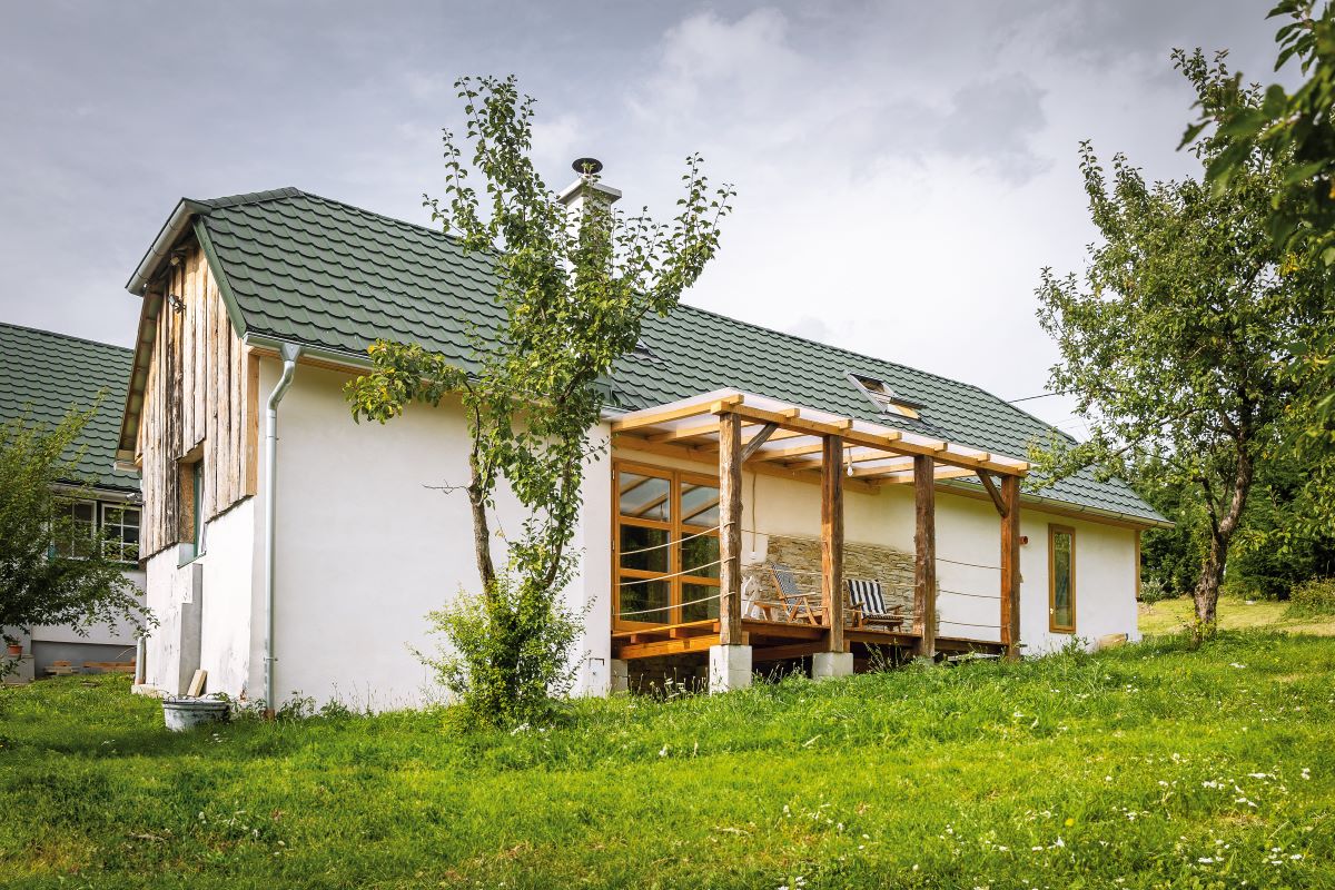 Zrekonštruovaná stodola s drevenou krytou terasou z exteriéru.