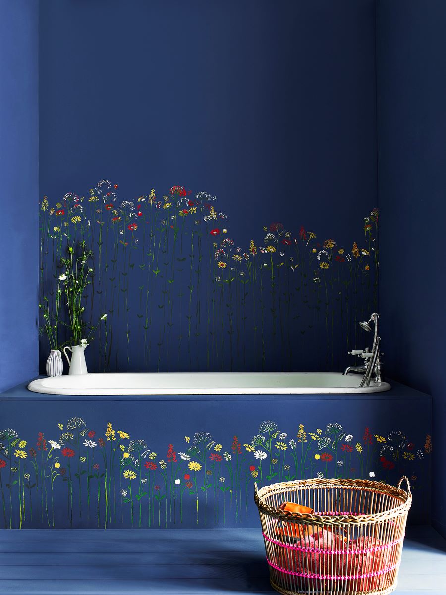 Záber na vaňu v sýtomodrom interiéri s kvetmi na stene a obložení vane.