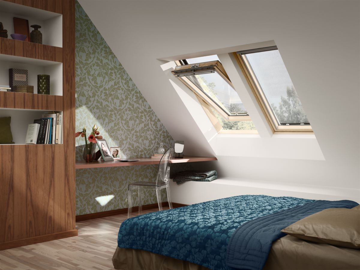 Časť podkrovnej spálne s posteľou, stolom, poličkou a strešnými oknami.