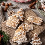 Švédske medovníky pepparkakor na drevenej doske na krájanie s ďalšími vianočnými koláčmi.