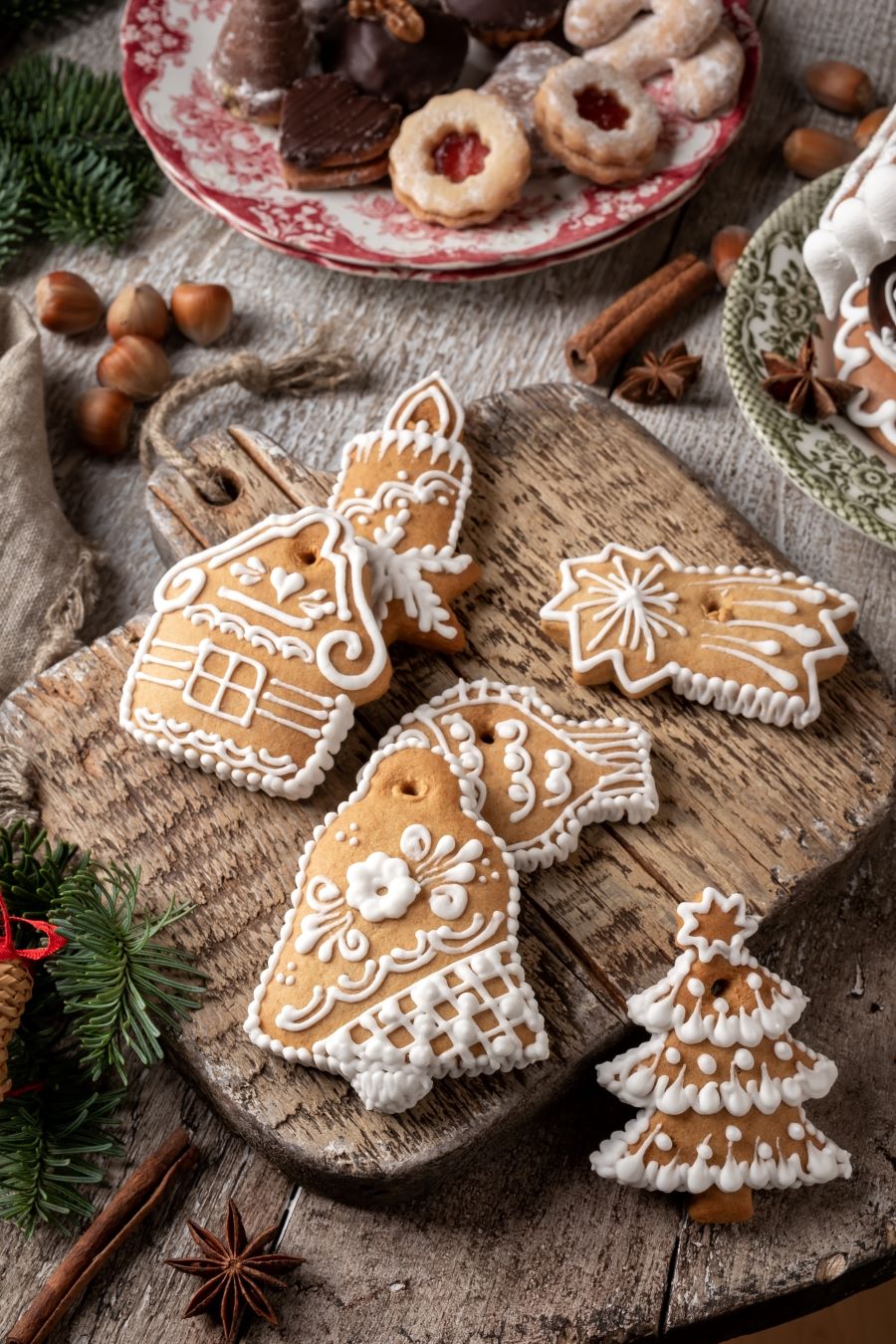 Švédske medovníky pepparkakor na drevenej doske na krájanie s ďalšími vianočnými koláčmi.