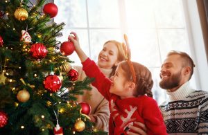 Mama, otec a dcéra pri ozdobovaní vianočného stromčeka.