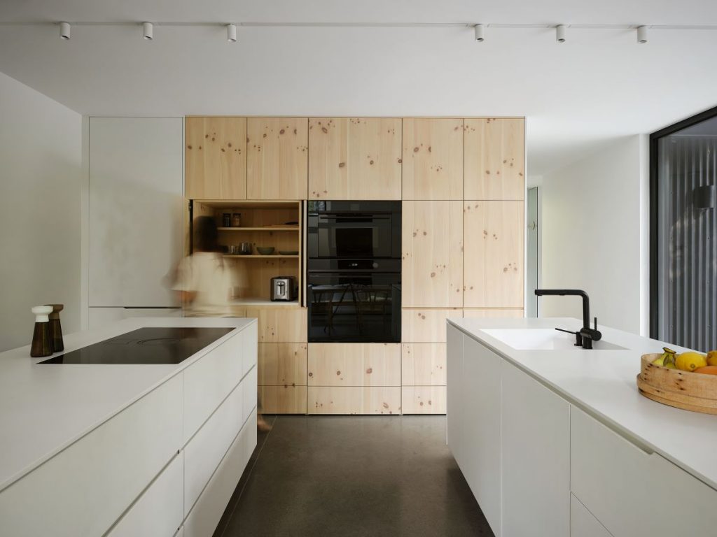 Záber na úložné priestory v kuchyni v drevenom dizajne so zabudovanými spotrebičmi.