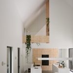 Záber z diaľky na kuchyňu v bielo-drevenom dizajne a mezanín nad ním.