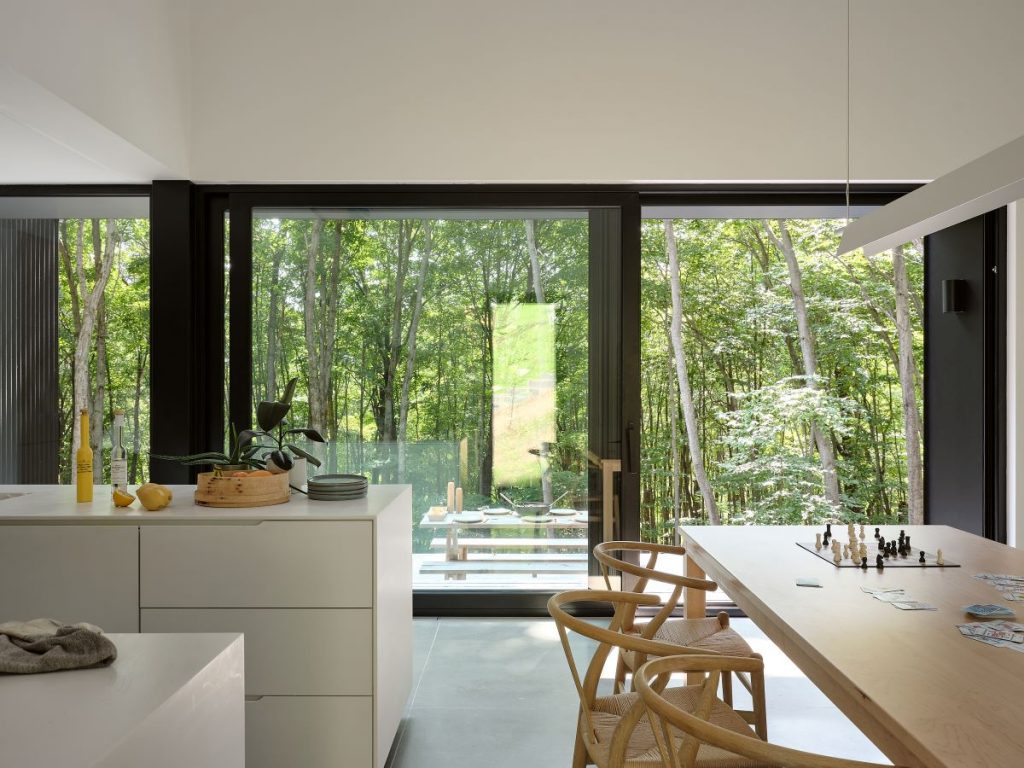 Pohľad z kuchyne cez presklené posuvné dvere na terasu a les.