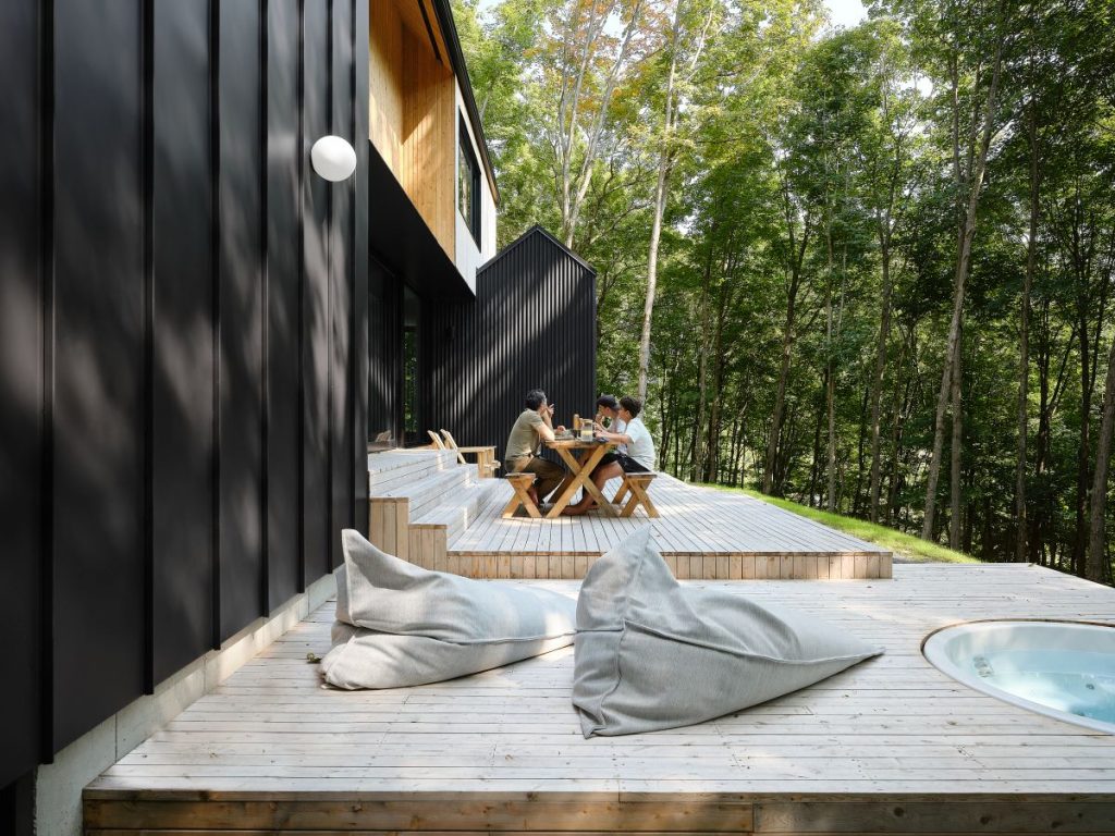 Štvorčlenná rodina si užíva jedno na drevenej terase pri chate v lese.