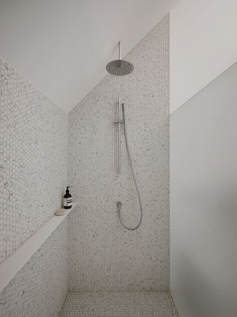 Pohľad na sprchovací kút s hexagónovým obkladom.