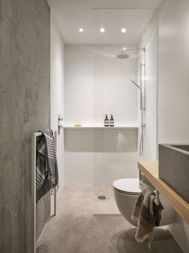 Pohľad do kúpeľne v minimalistickom dizajne s toaletou a sprchovacím kútom.
