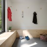 Časť vstupného priestoru s dreveným sedením a vešiakmi na stene.