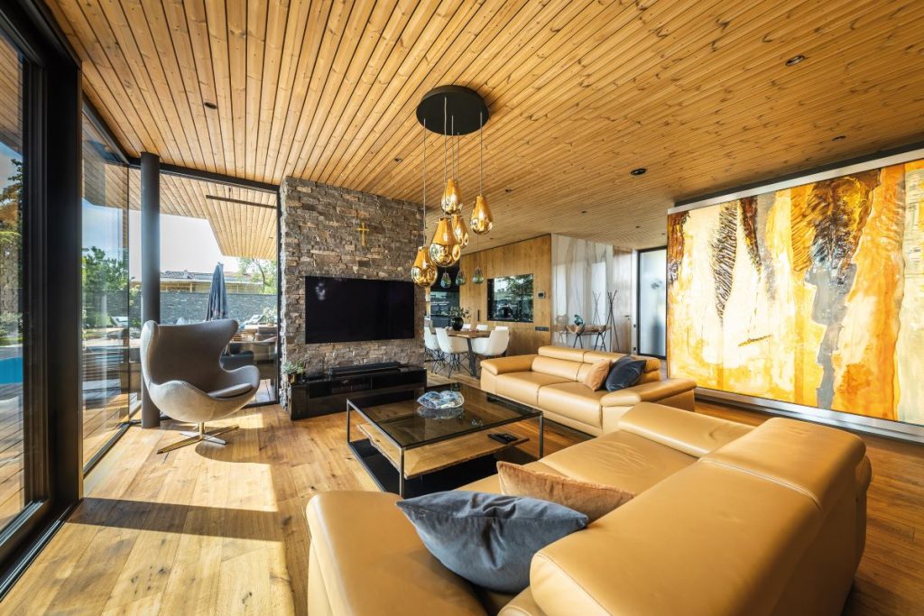 Obývačka domu s televízorom, koženými sedačkami a umeleckým dielom.
