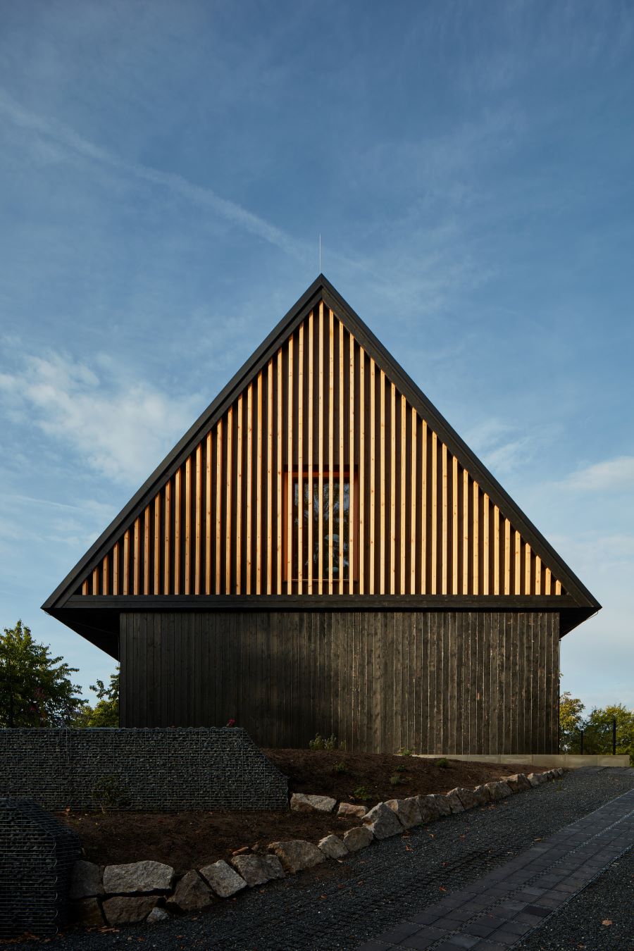 Dom inšpirovaný chatou s drevenou fasádou a výrazným priečelím od ulice.