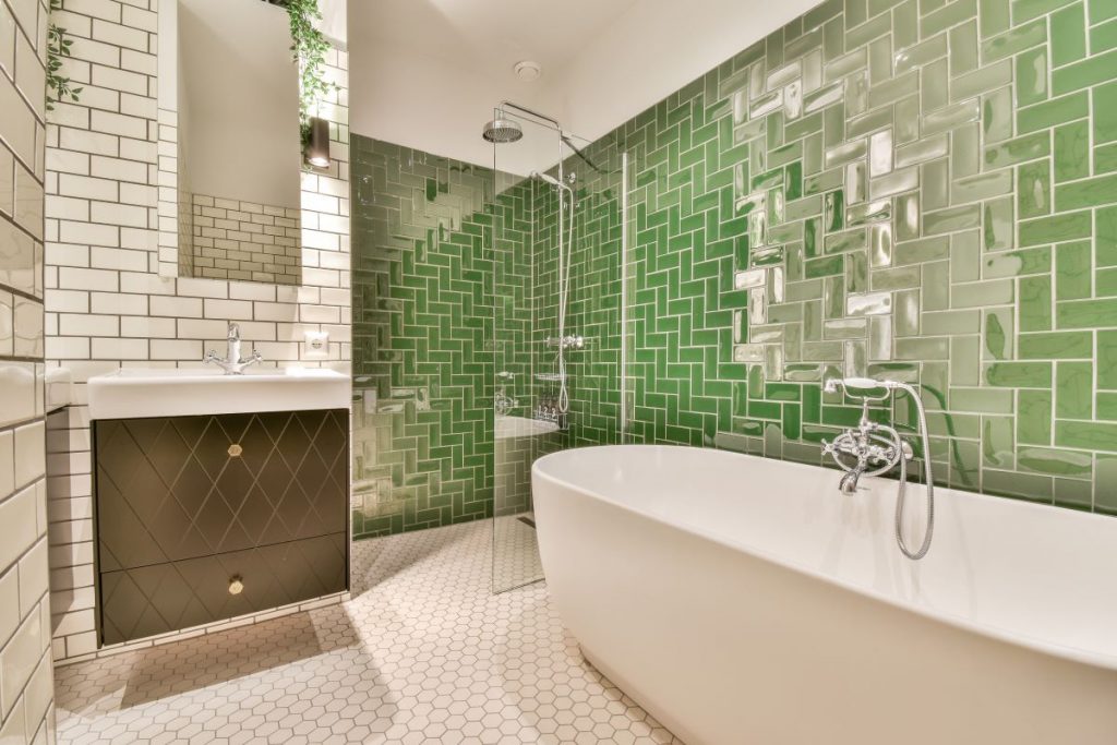 Bielo-zelená kúpeľňa s vaňou a rôznymi vzormi obkladu.