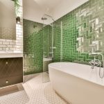 Bielo-zelená kúpeľňa s vaňou a rôznymi vzormi obkladu.