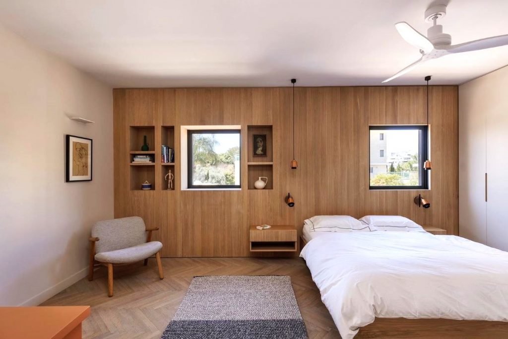 Jedna zo spální v dome s posteľou, a dreveným obložením s nikami na jednej zo stien.