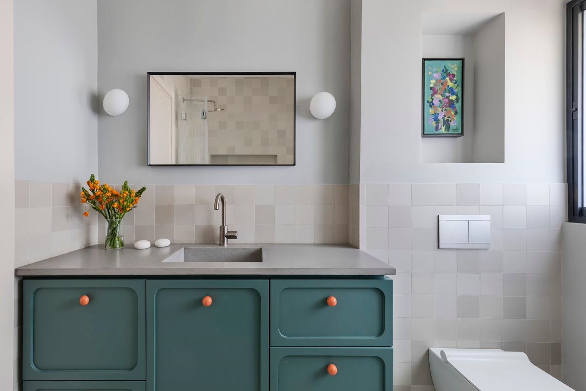 Jedna z kúpeľní v dome s toaletou a farebnou skrinkou s integrovaným umývadlom.