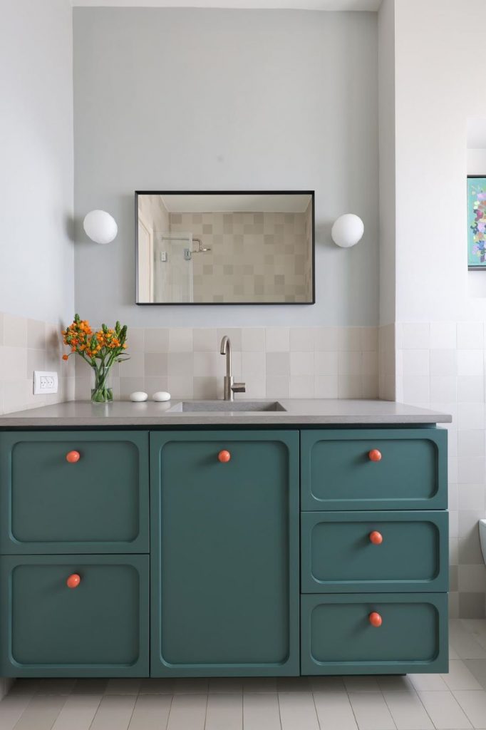 Jedna z kúpeľní v dome s farebnou skrinkou s integrovaným umývadlom.