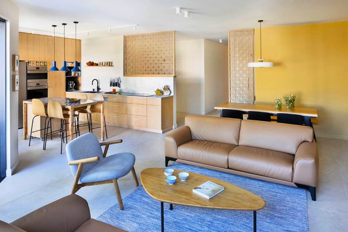 Obývačka s koženými sedačkami a stolíkom, spojená s jedálňou a kuchýňou.