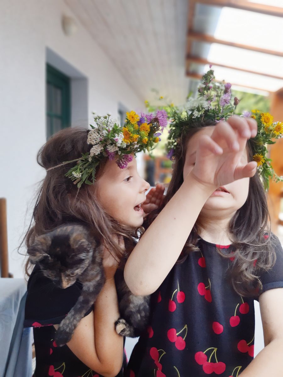 Dve dievčatá s kvetovými venčekmi na hlavách v exteriéri.