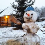 Záber na snehuliaka s metlou a hrncom v exteriéri pred domom.
